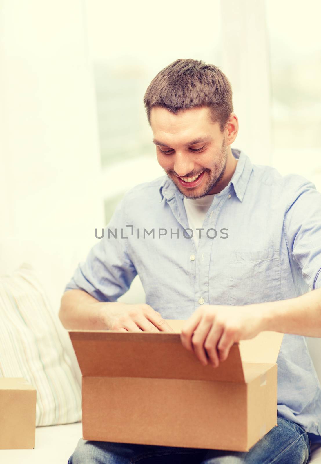 post, home and lifestyle concept - smiling man with cardboard boxes at home