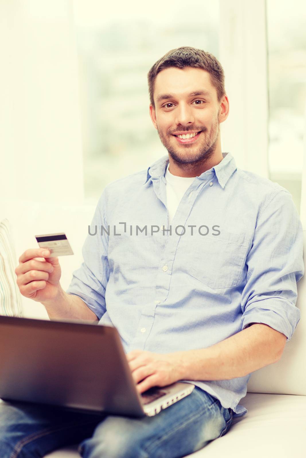 technology, home and lifestyle concept - smiling man working with laptop and credit card at home