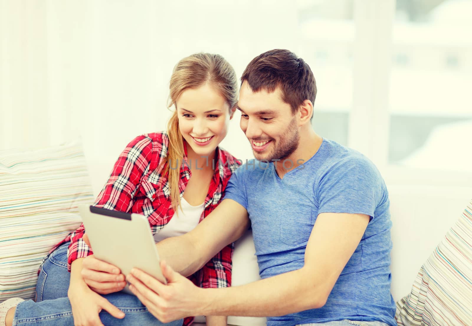 smiling couple with tablet pc computer at home by dolgachov