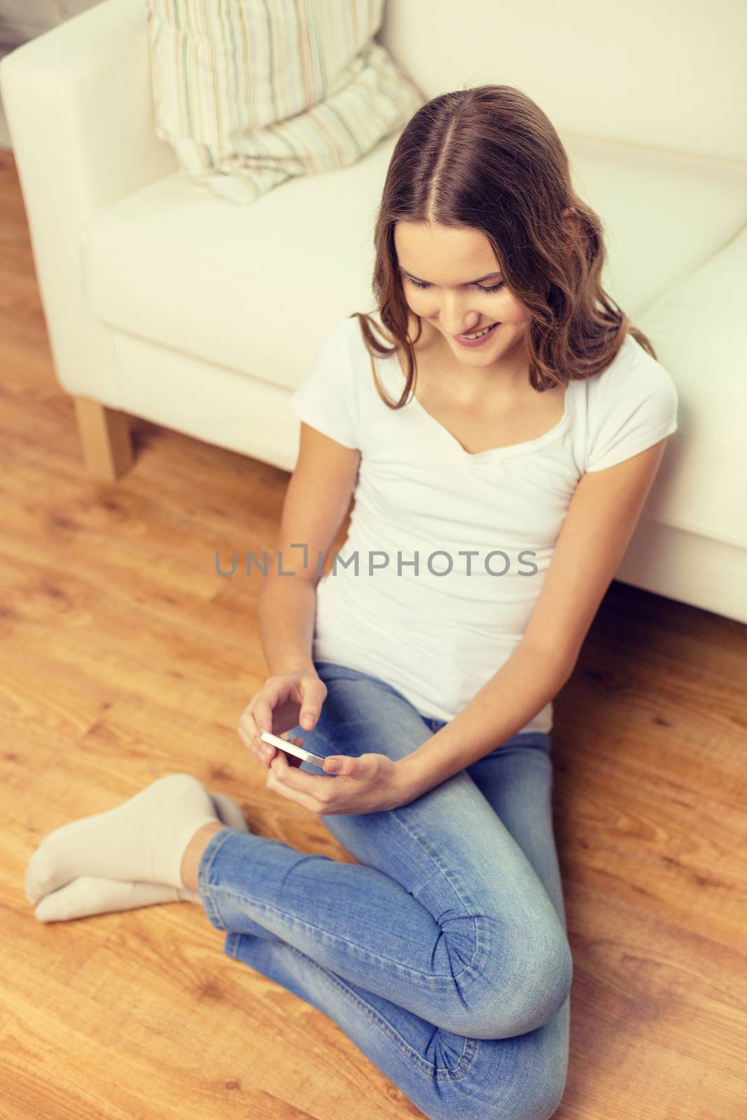 home, technology and internet concept - smiling teenage girl sitting on the floor with smartphone at home