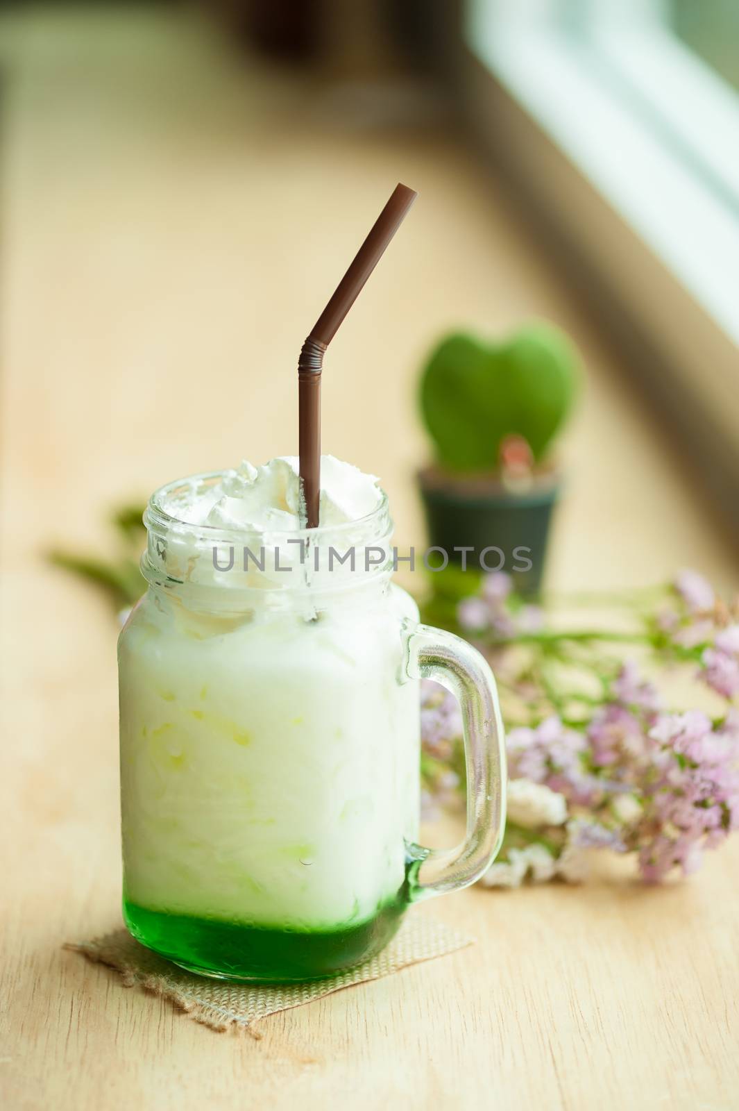 Fresh milk with green syrup on wood bar in cafe.