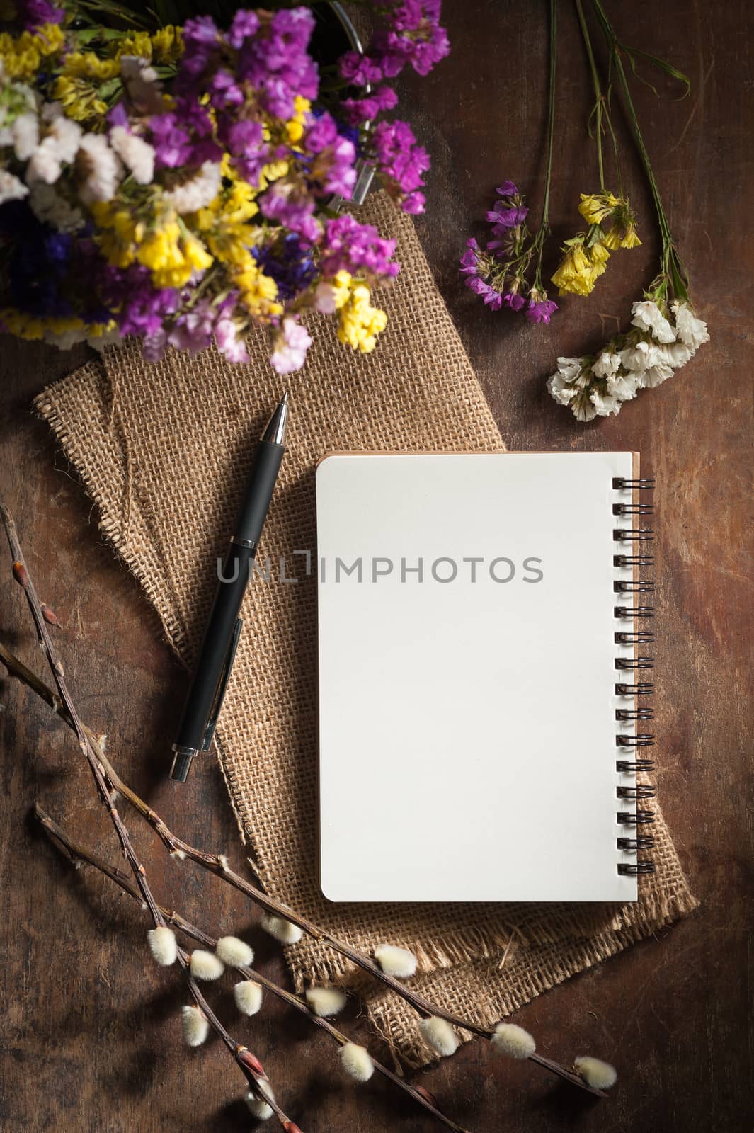 Small notepad with pen on rustic wood background with film filter effect