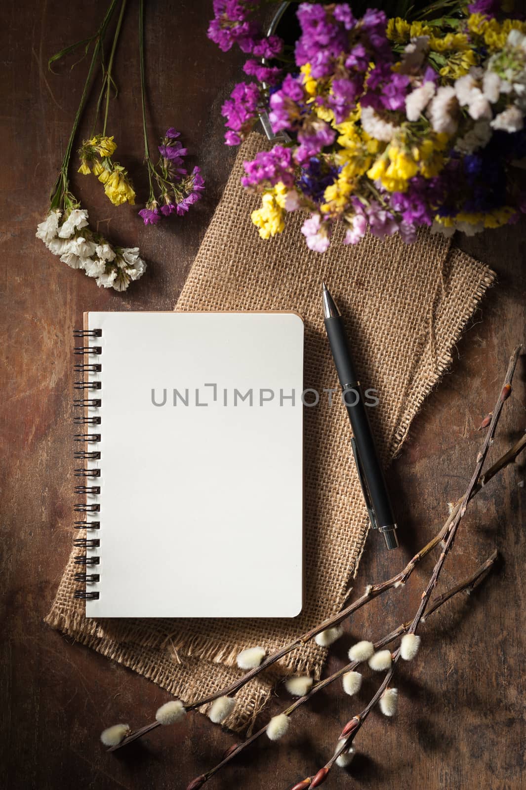 Small notepad with pen on rustic wood background with low key scene.