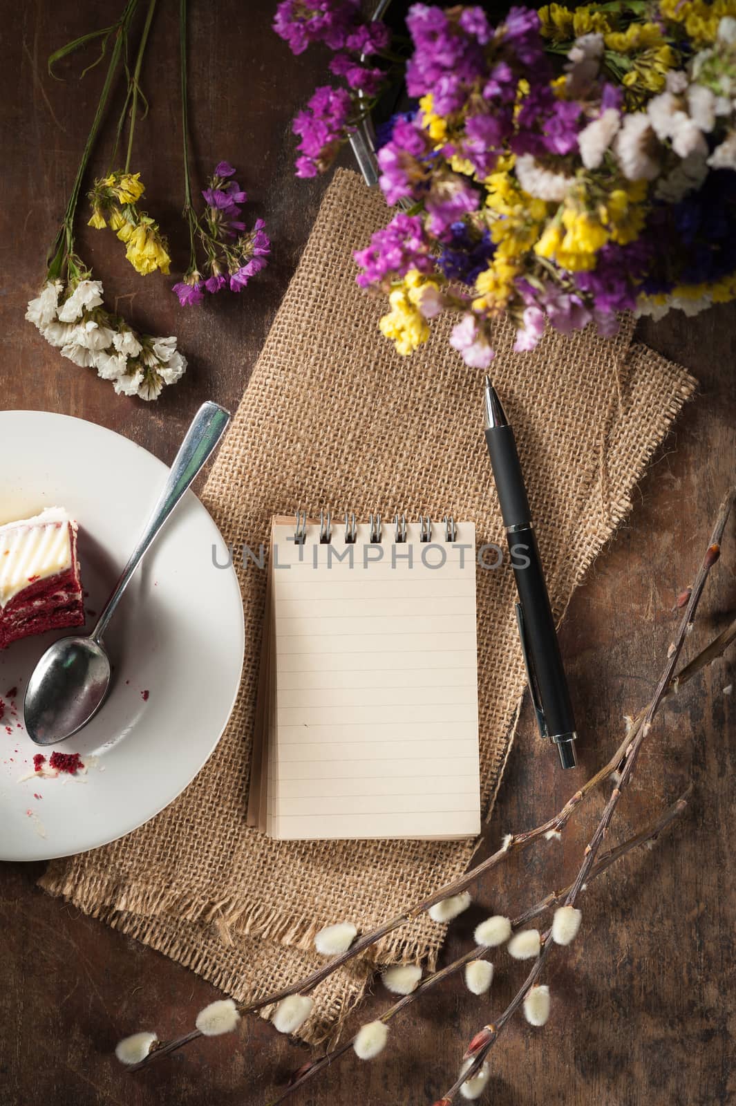 Small notepad with pen and pencil on rustic wood background with low key scene.