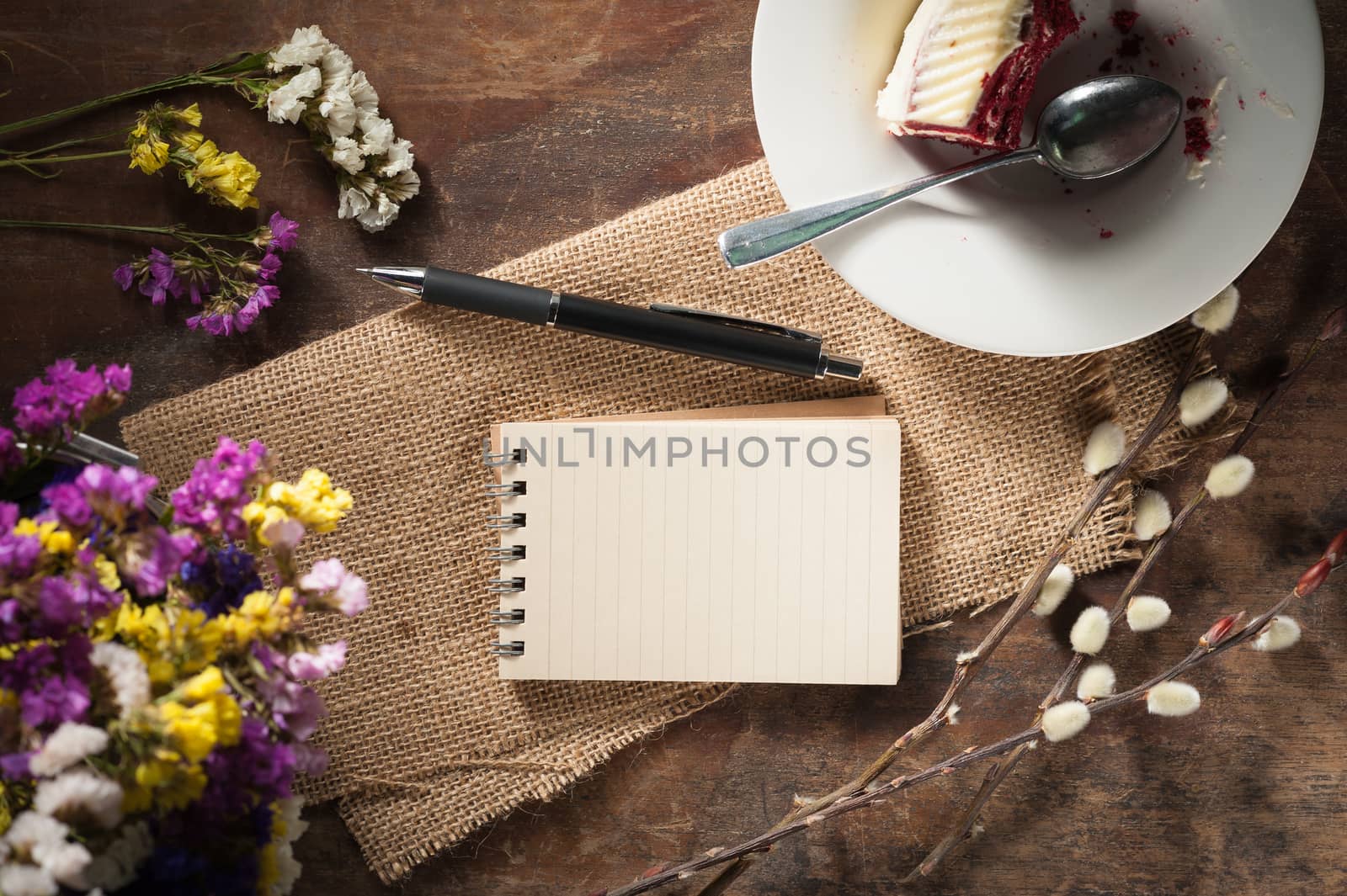 Small notepad with pen and pencil on rustic wood background with low key scene.