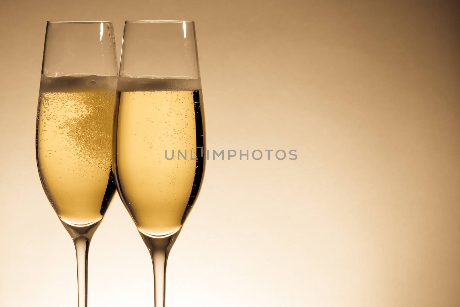 two glasses of champagne with golden bubbles by donfiore
