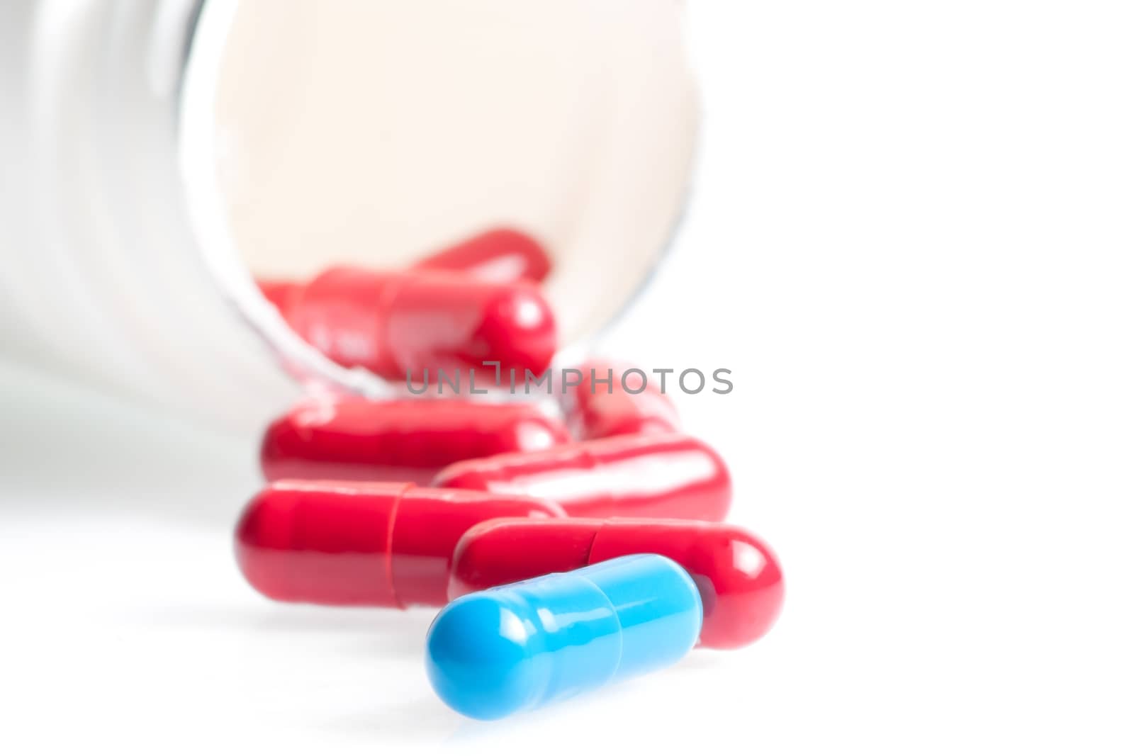 blue and red medical pills in laboratory near white container on white table with space for text