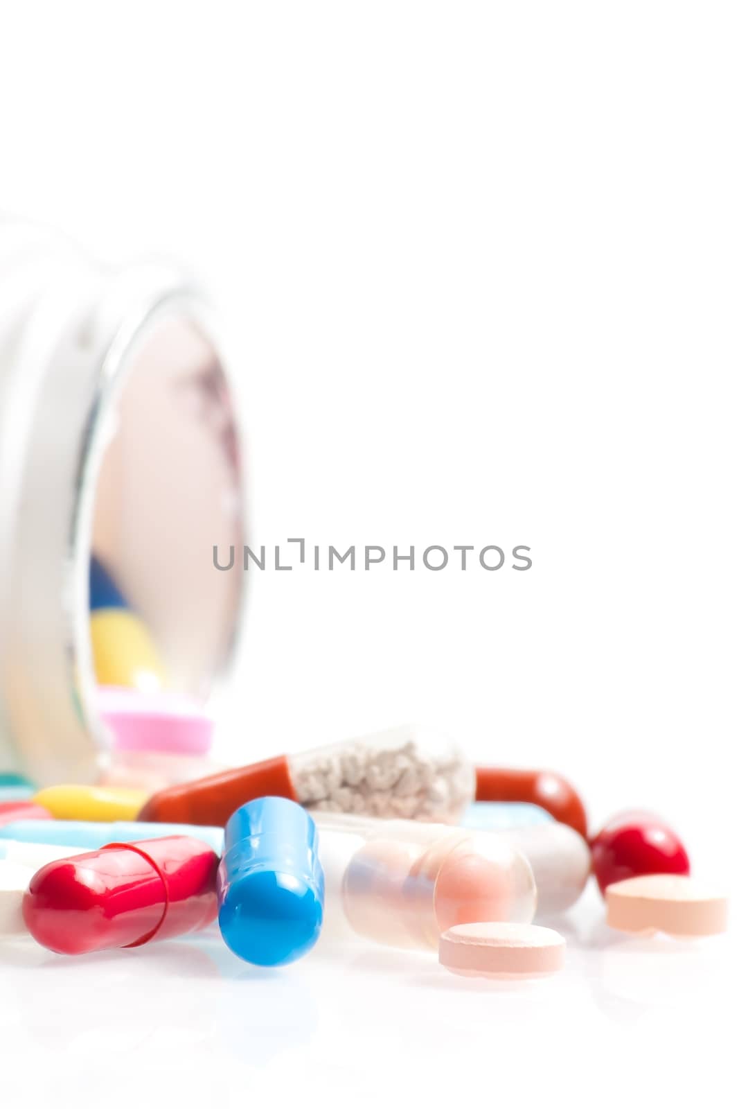 colored pills in laboratory in front of a white container on white table