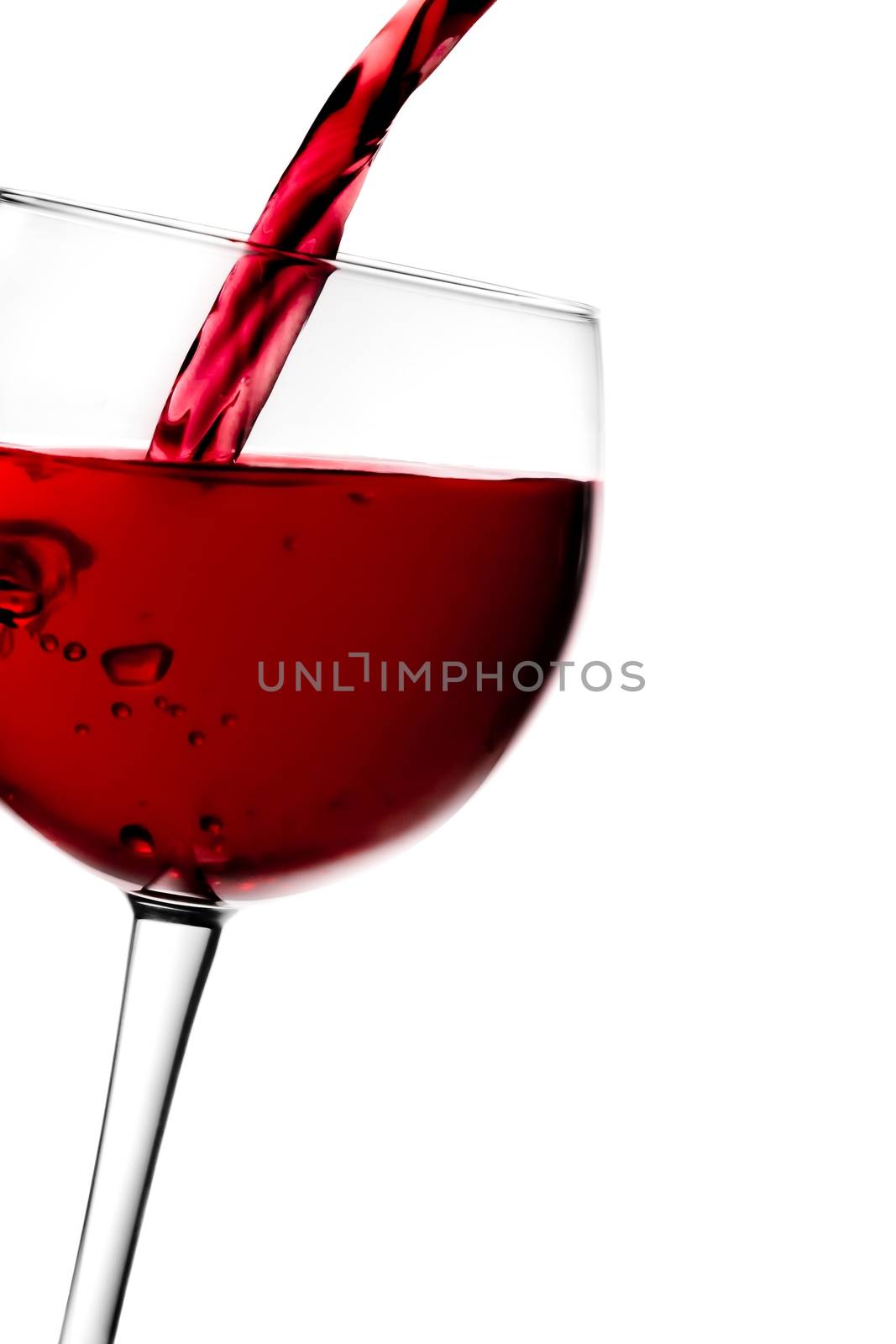 red wine pouring into half glass tilted with space for text on a white background