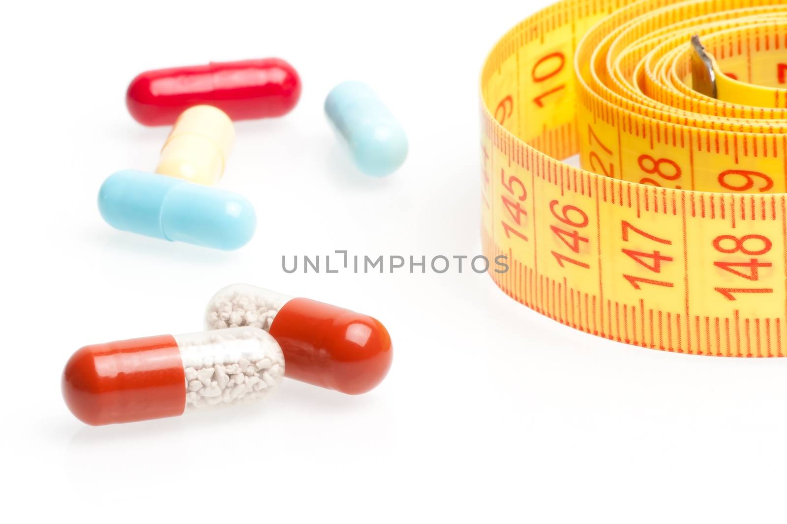 measuring tape and pills for dieting on a white background