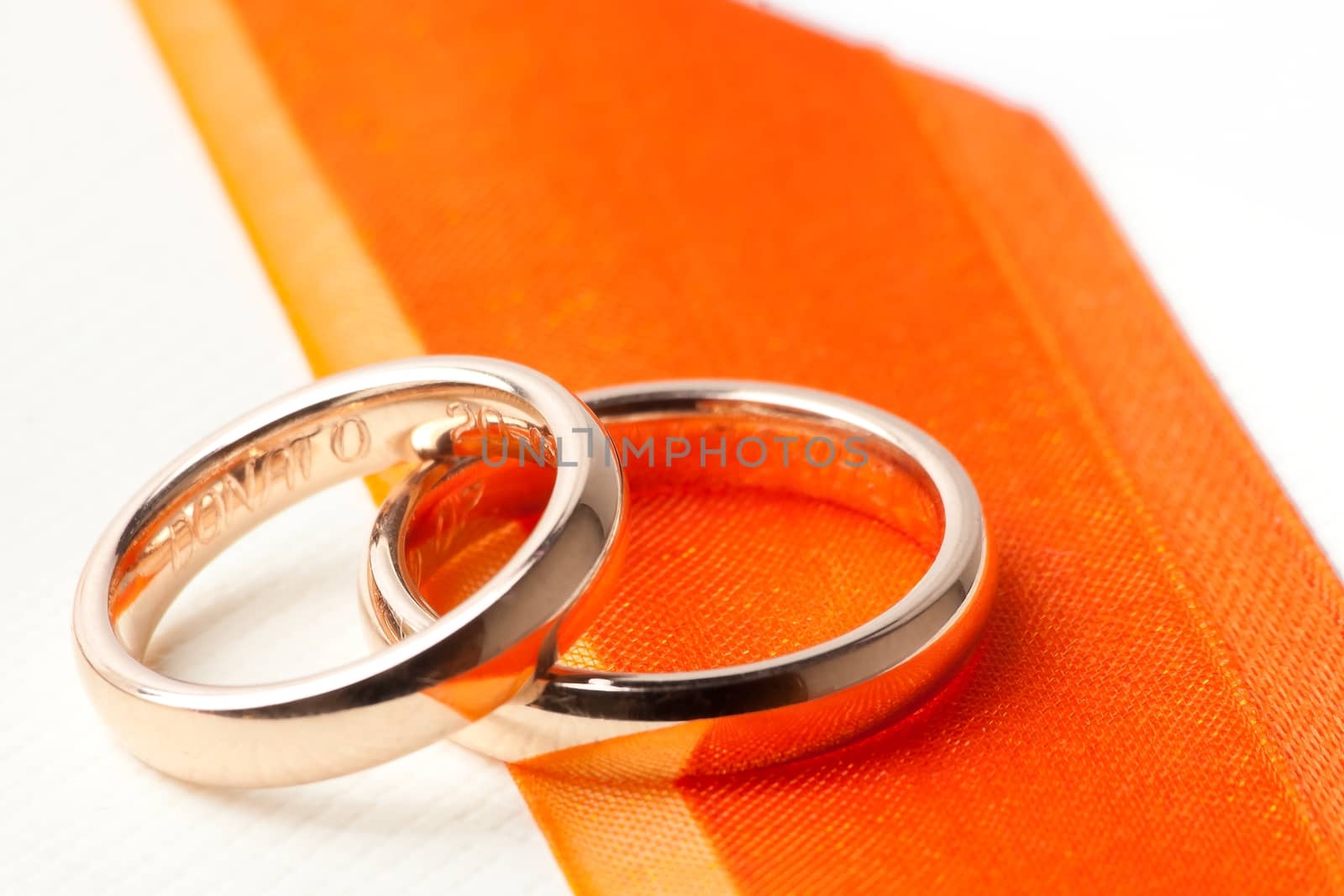 gold wedding rings near orange ribbon by donfiore