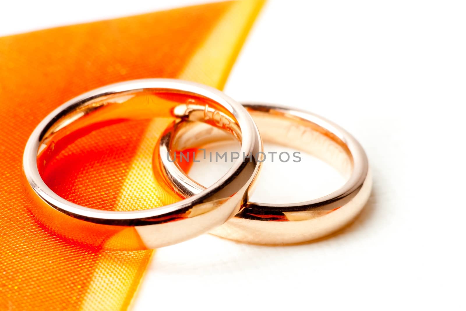 detail of gold wedding rings near orange ribbon
