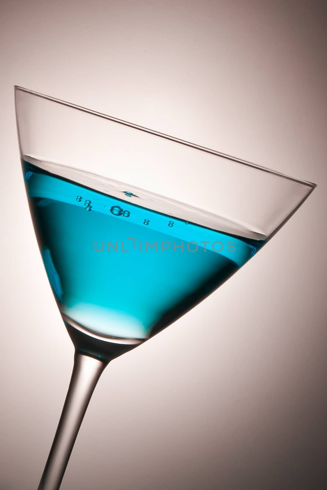 glass with blue cocktail tilted by donfiore