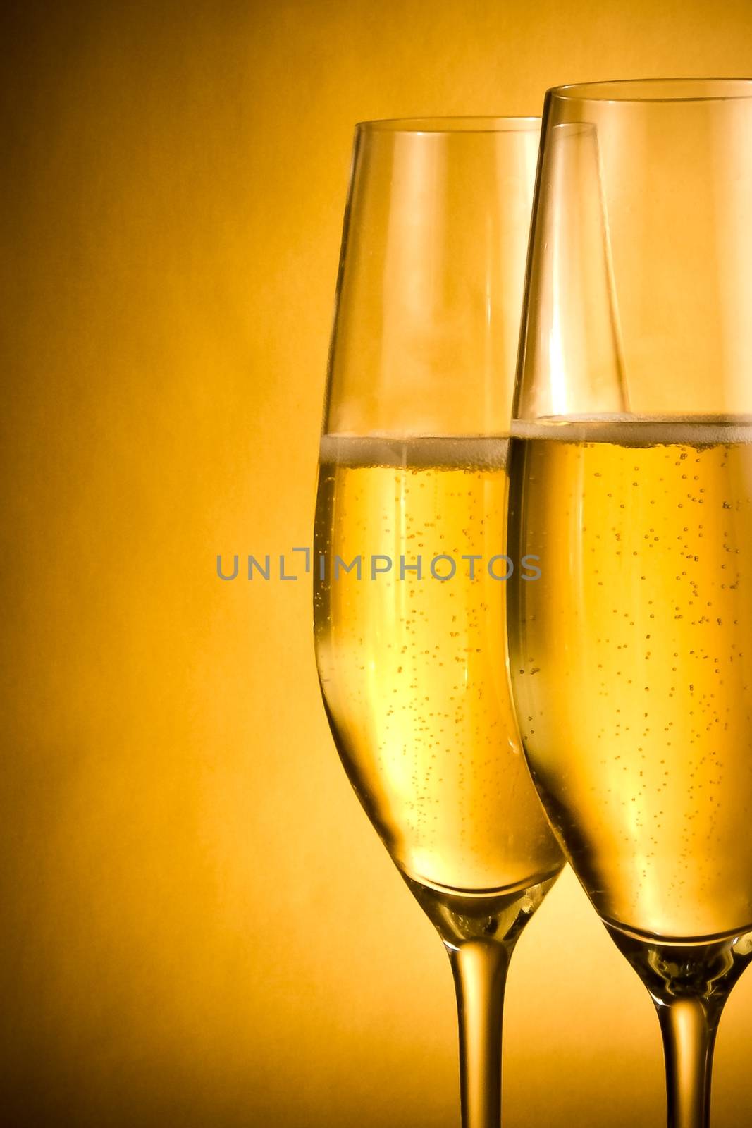 two flutes of champagne with golden bubbles and space for text against golden background