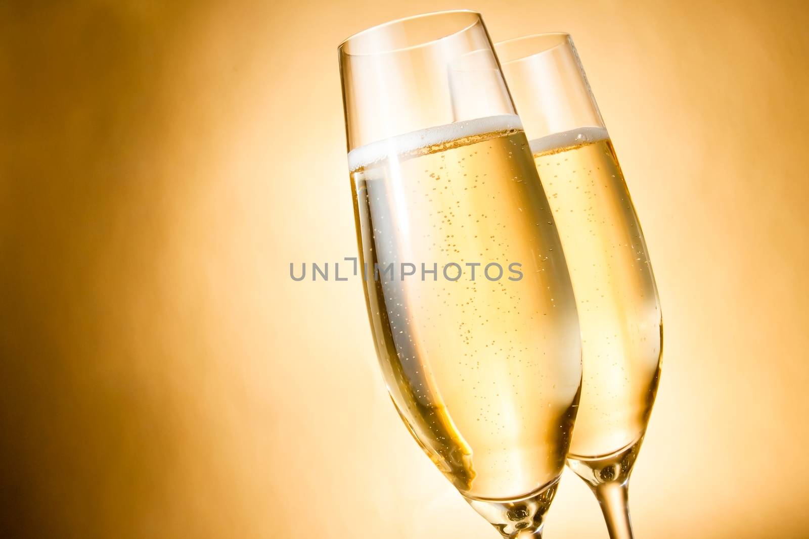 two glasses of champagne with golden bubbles and space for text by donfiore