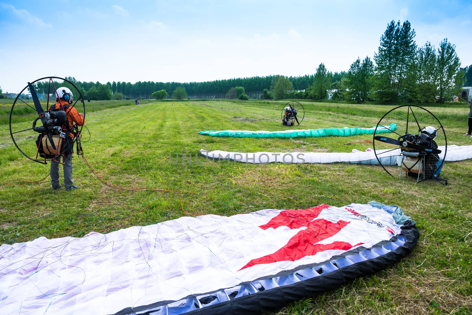 motorized paragliders are ready to go from a green field by Isaac74