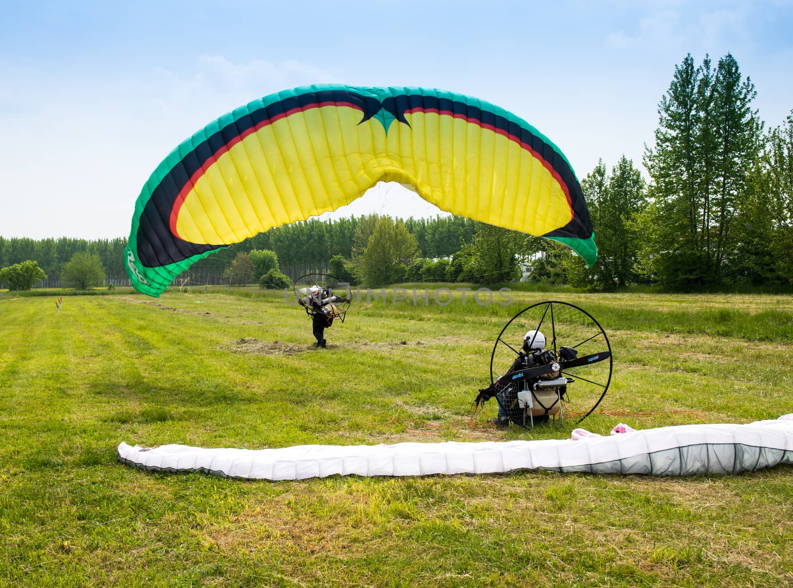 man with motorized paraglider takes off from a field by Isaac74