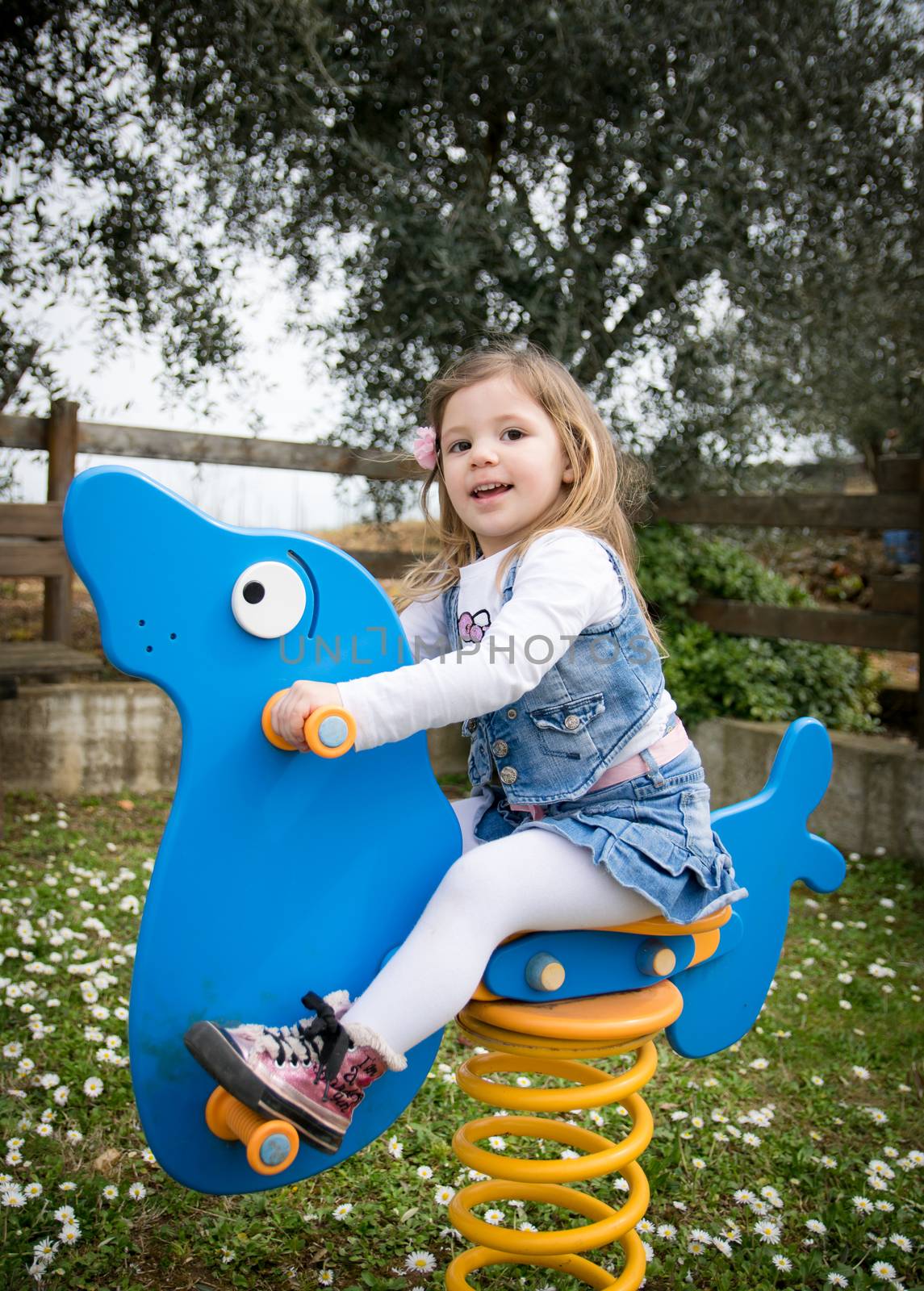 child plays on a blue spring seal in an outdoor playground