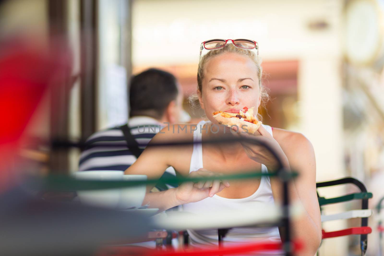 Woman eating pizza outdoor in cafeteria. by kasto