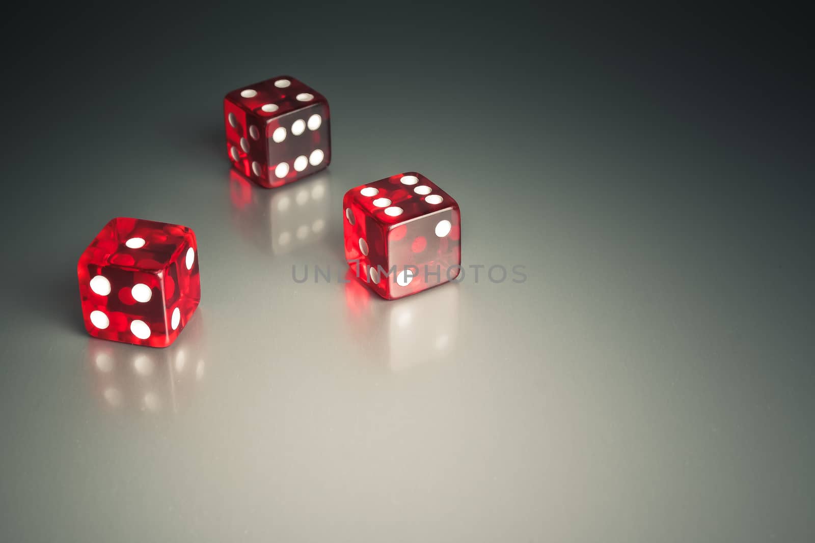 three red dice in the corner on a silver gaming table