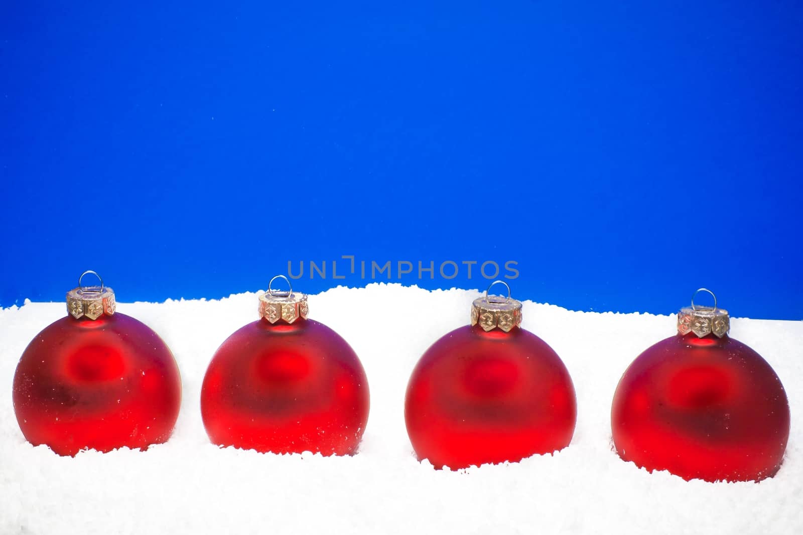 four christmas balls on the snow on blue background