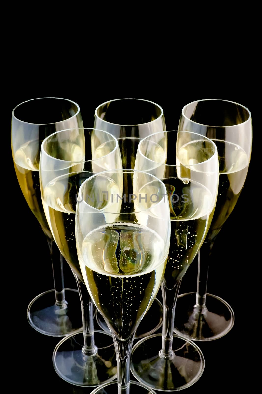detail of six glasses of champagne on black background with space for text