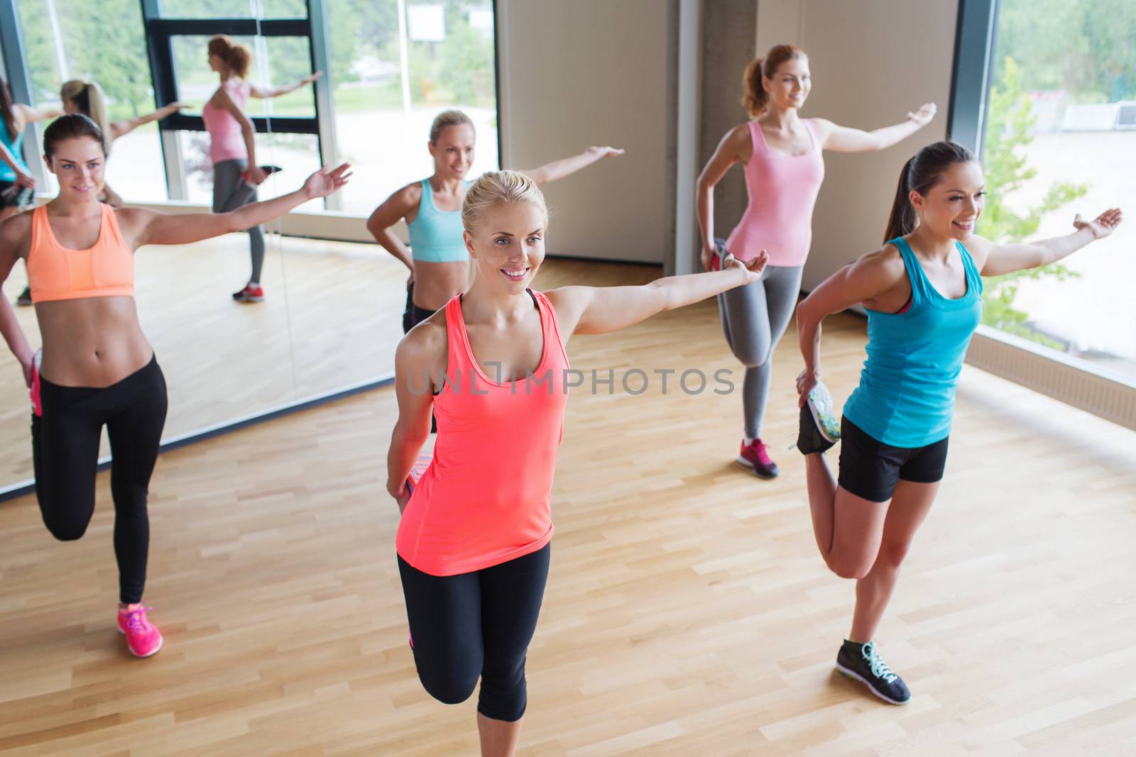 fitness, sport, training, people and lifestyle concept - group of women stretching leg in gym