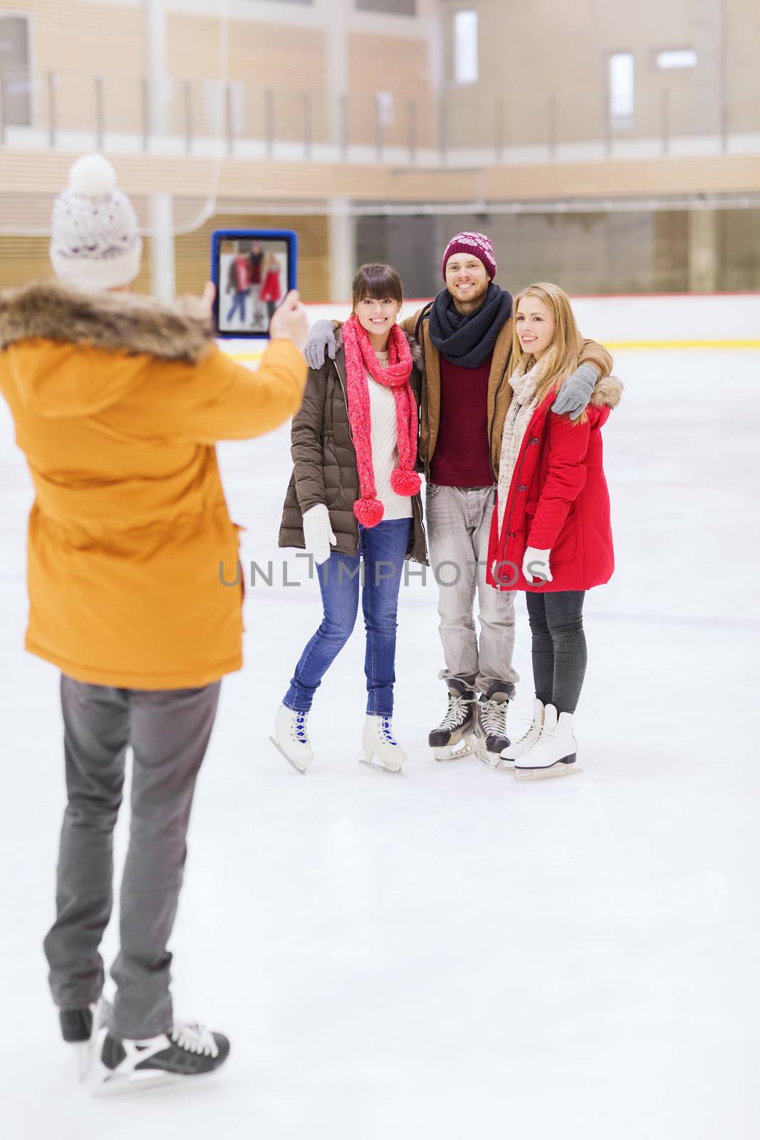 happy friends taking photo on skating rink by dolgachov