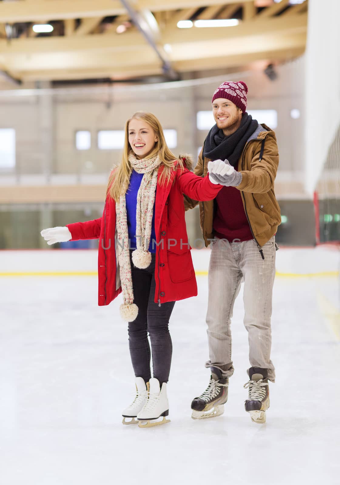 people, friendship, sport and leisure concept - happy couple on skating rink