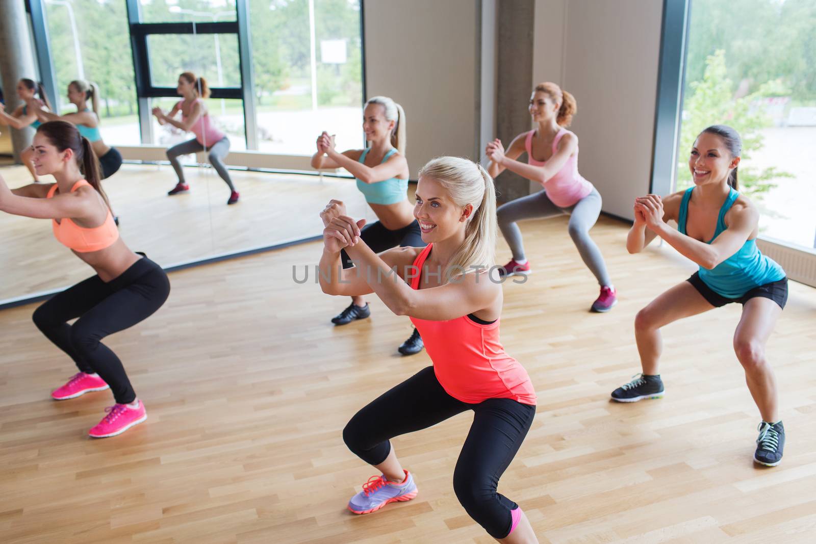 fitness, sport, training, people and lifestyle concept - group of women making squats in gym