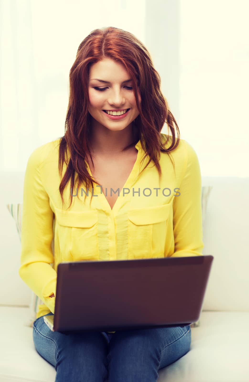 home, technology and internet concept - smiling woman sitting on the couch with laptop computer at home