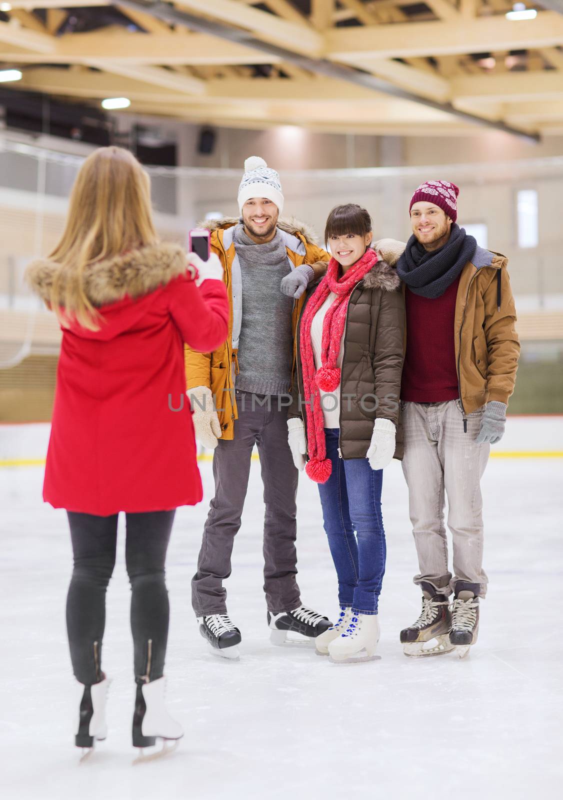 happy friends taking photo on skating rink by dolgachov