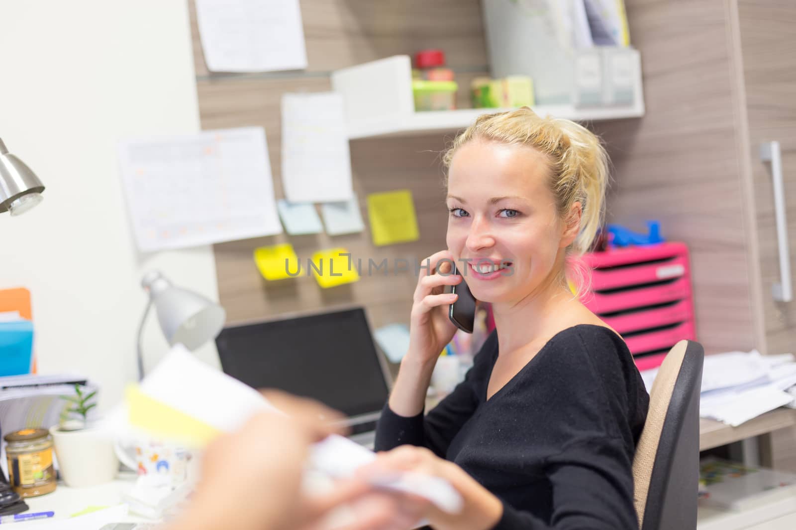 Businesswoman talking on mobile phone in office. by kasto