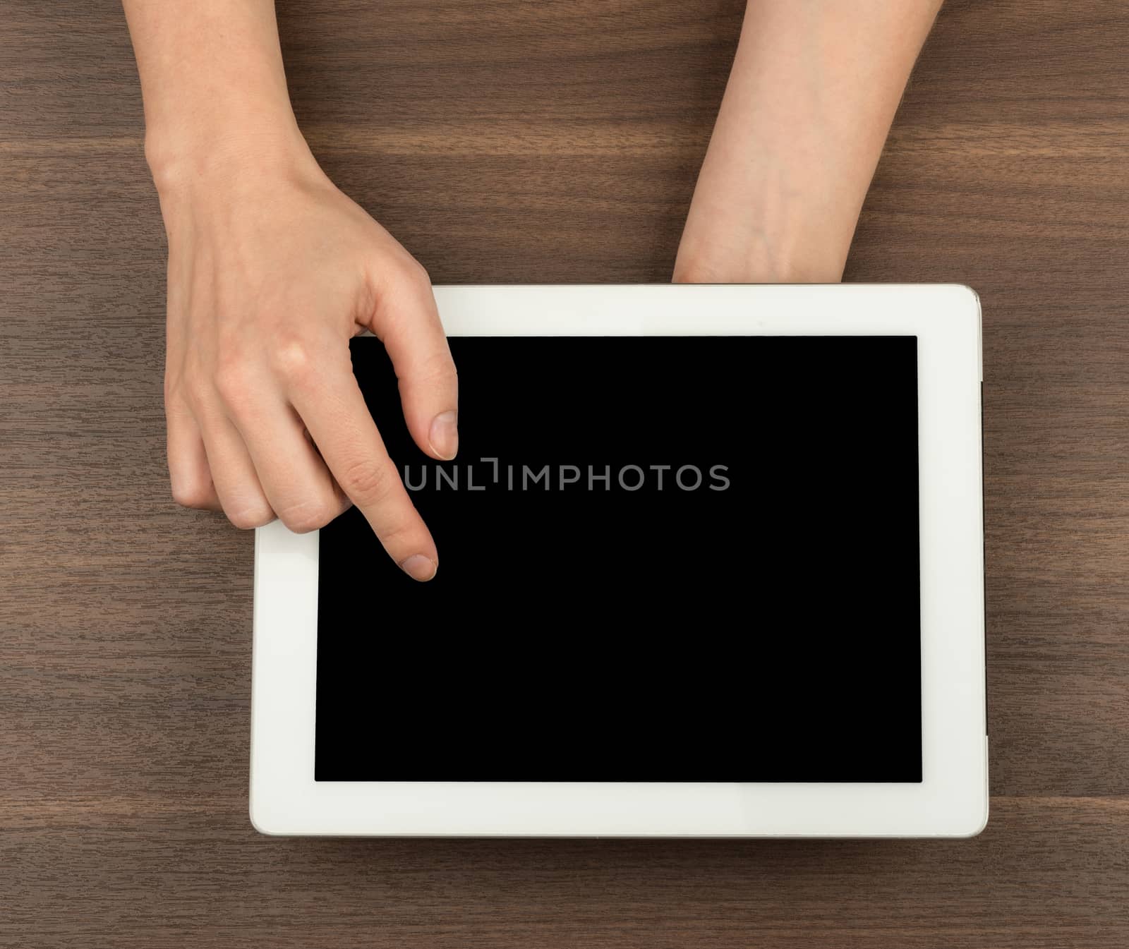 Humans hands pressing on tablet on wooden table background