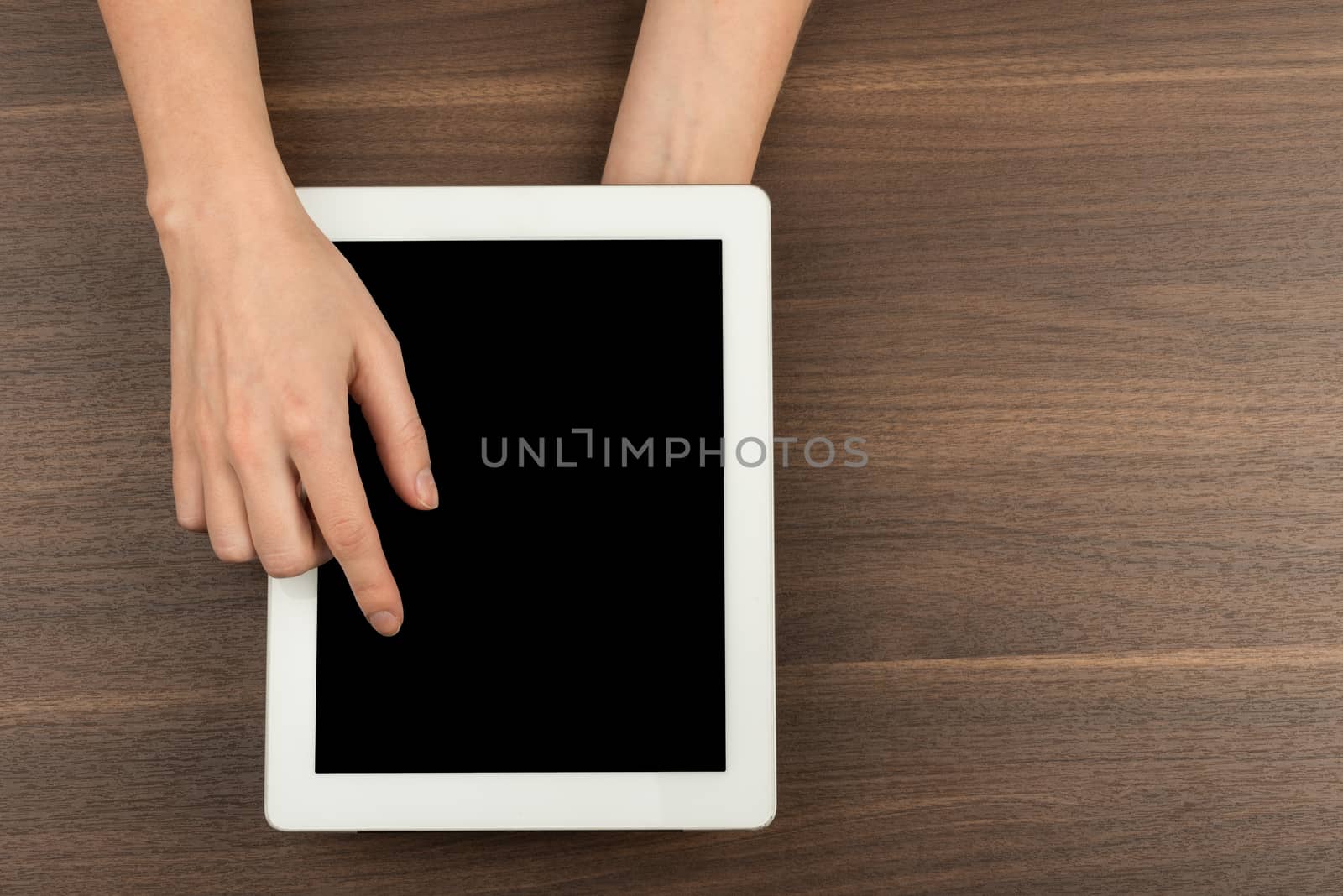 Womans hands pressing on tablet on wooden table background