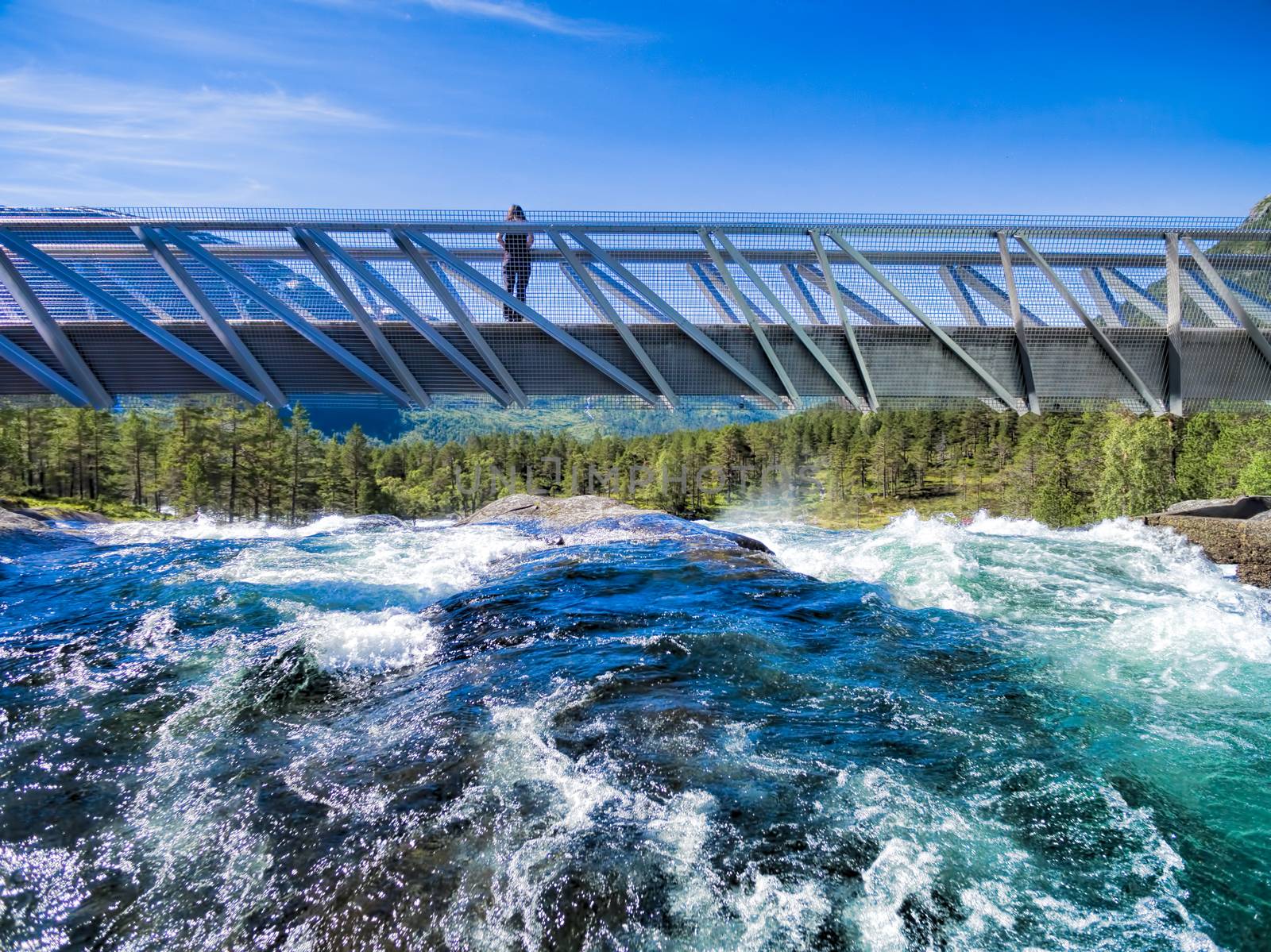 Girl standing on bridge above waterfall Likholefossen on Gaularfjellet tourist national road in Norway