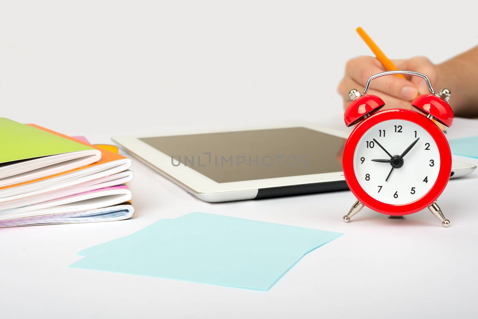 Womans hand with pencil and alarm clock on isolated white background