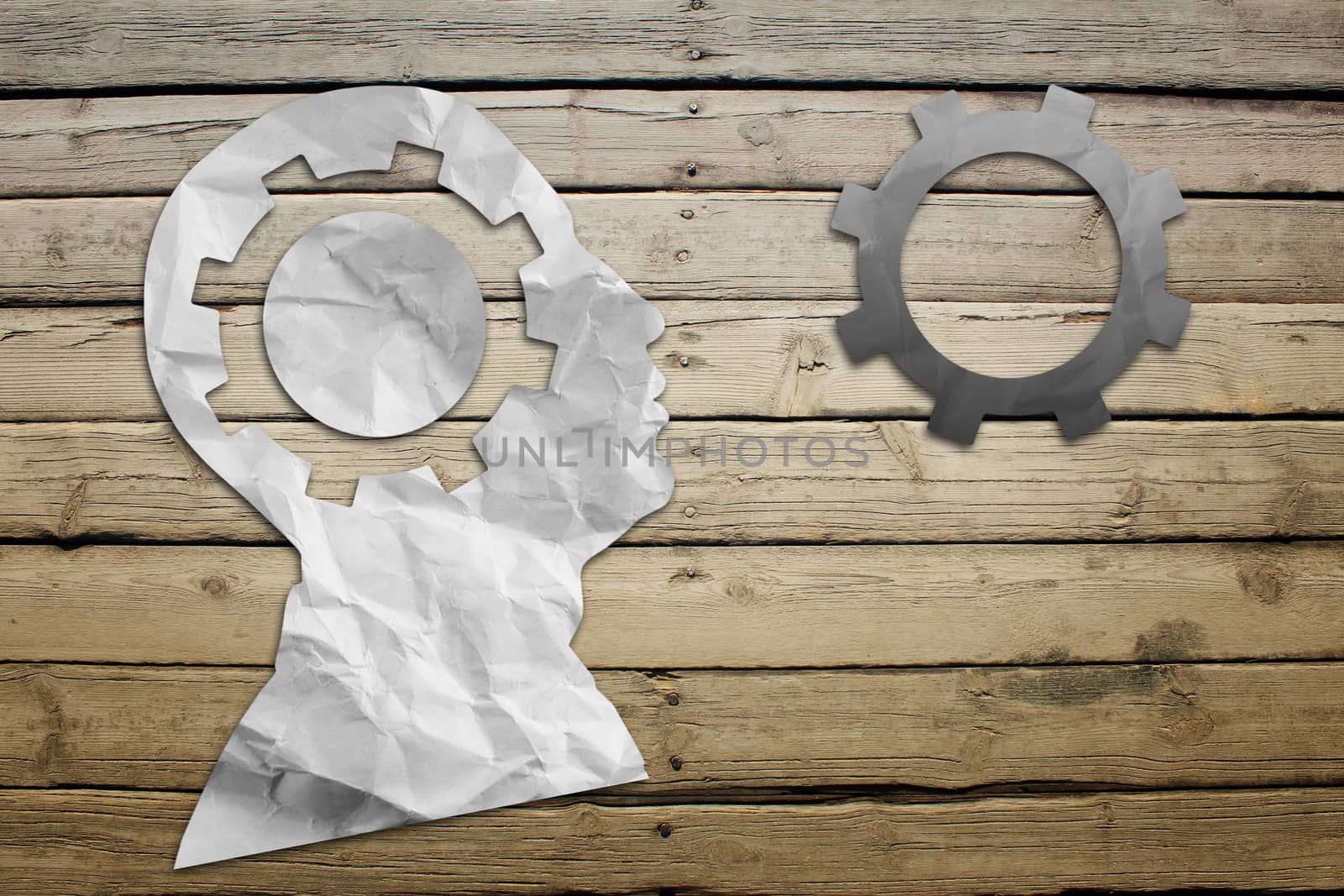 Paper humans head with wheel symbol on wood deck background