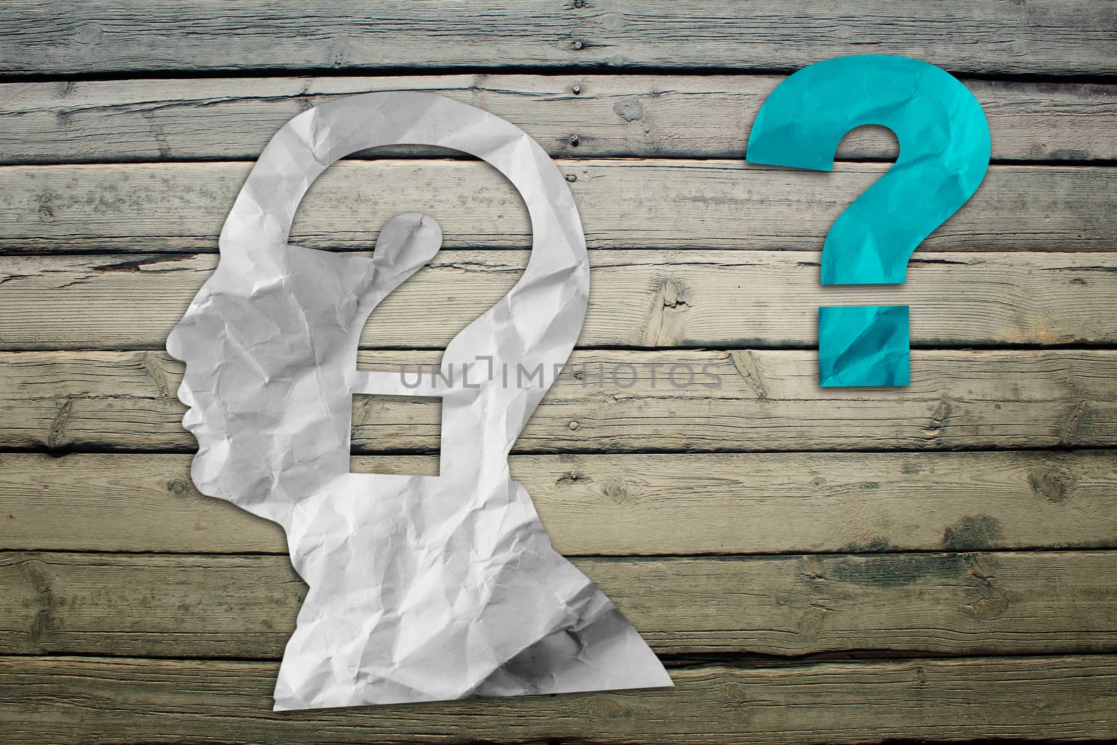 Paper humans head with question symbol on wood deck background