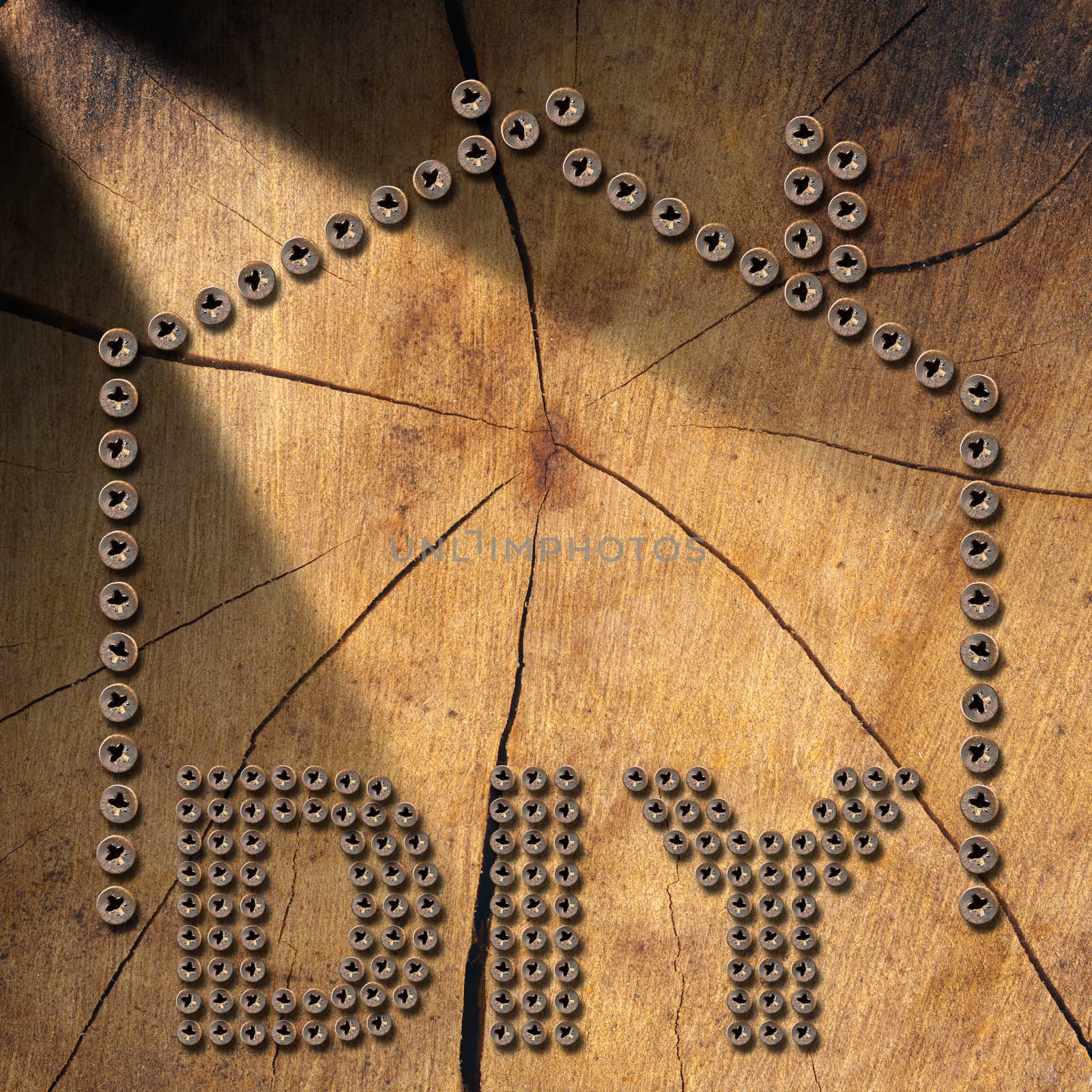 Many screws in the shape of text Diy (Do it yourself) and a house, on a brown wooden background.