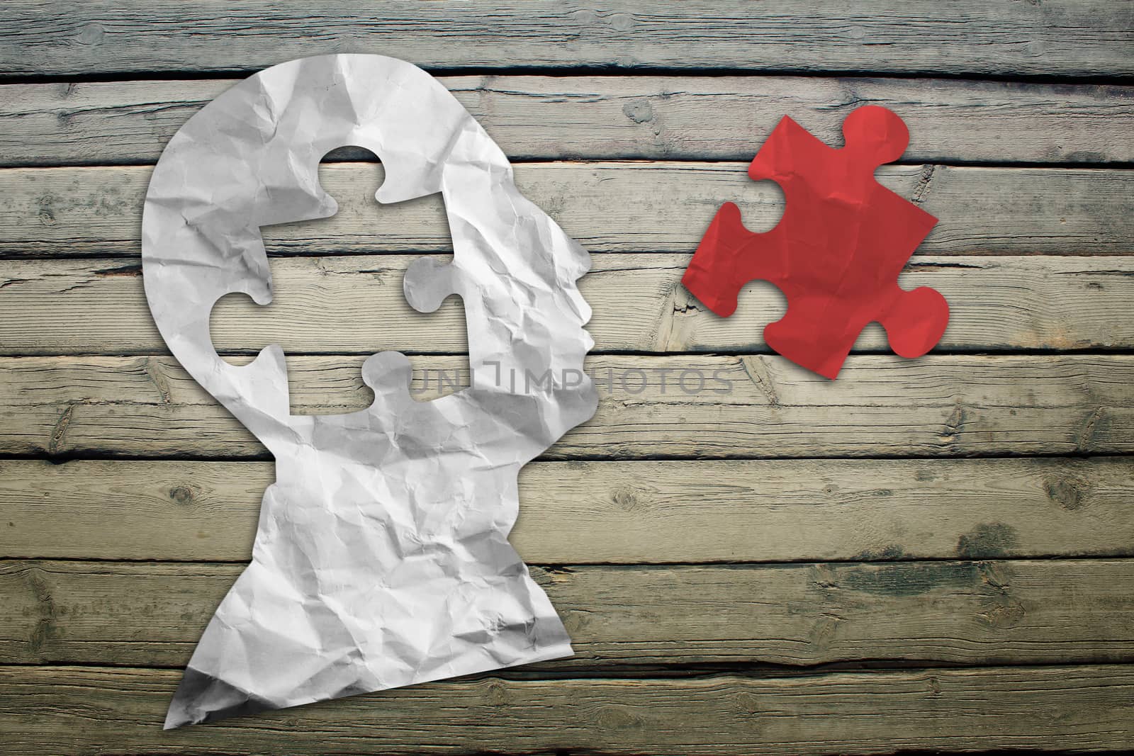 Paper humans head with puzzle symbol on wood deck background