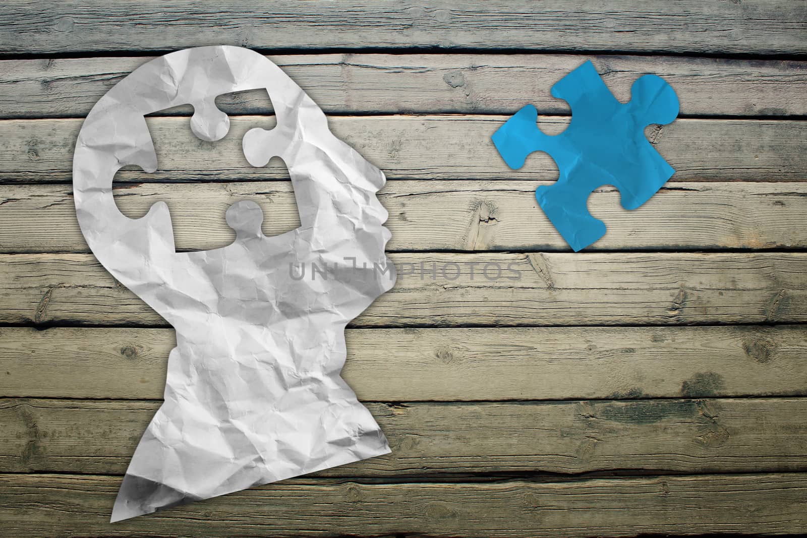 Paper humans head with puzzle symbol on wood deck background