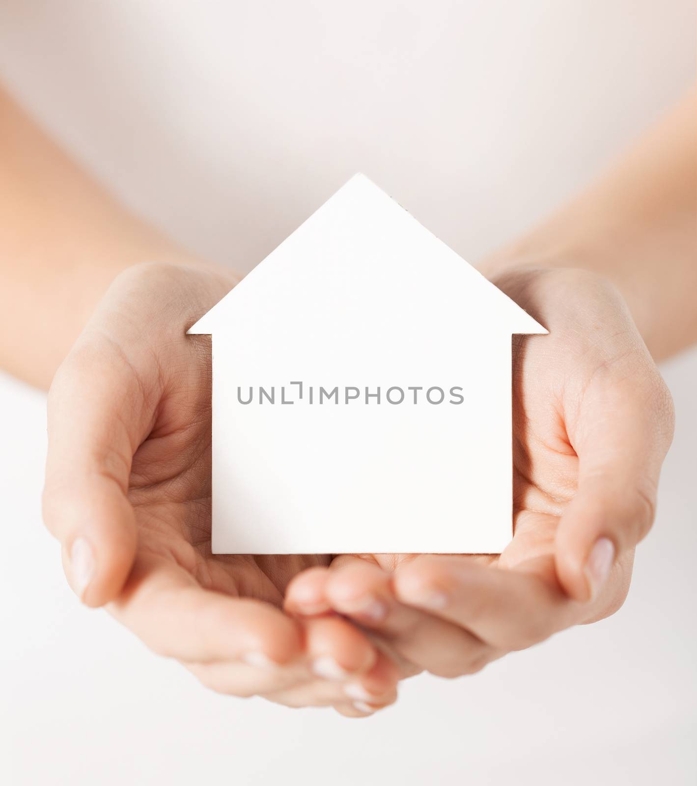 real estate and family home concept - closeup picture of female hands holding white blank paper house