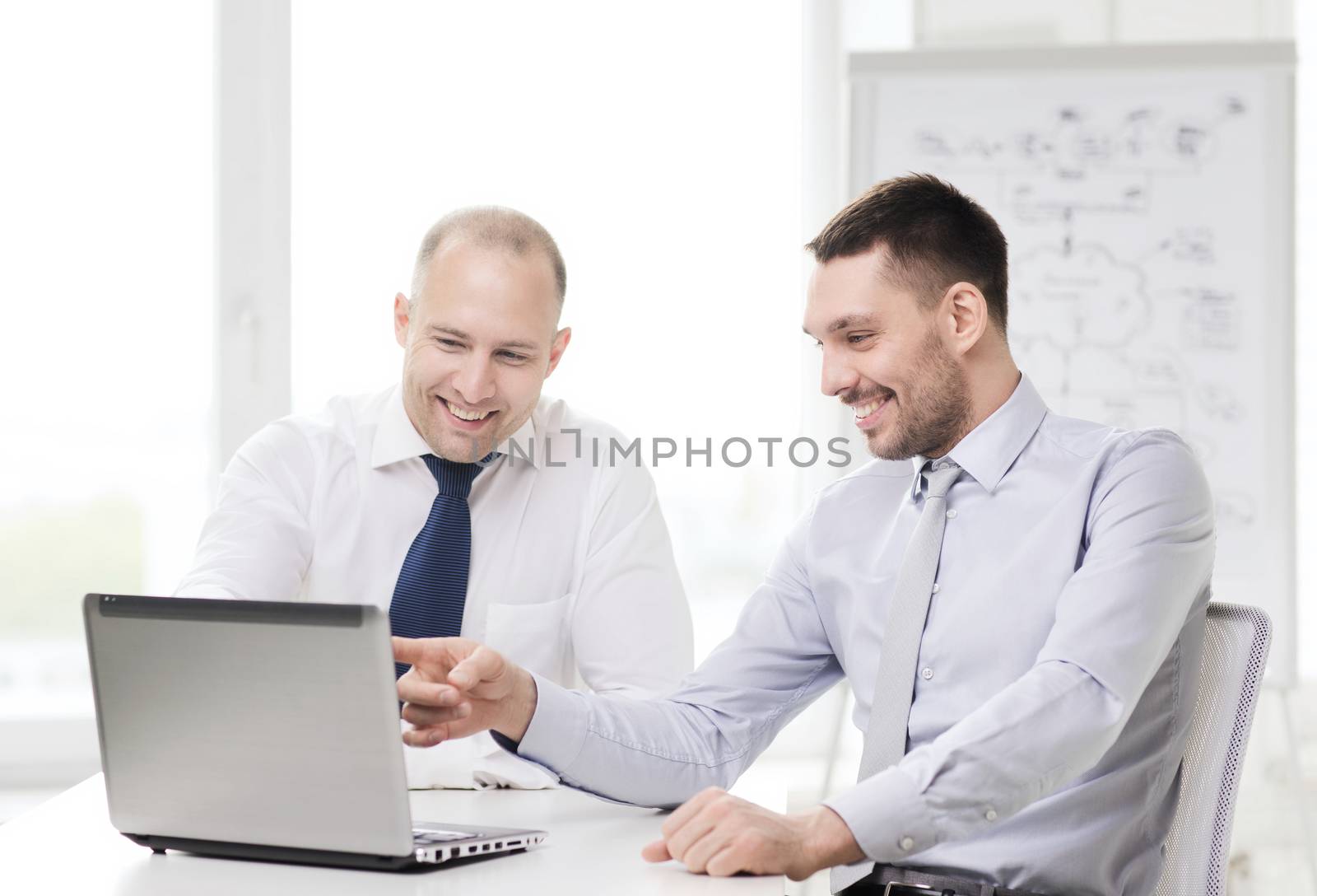 two smiling businessmen with laptop in office by dolgachov