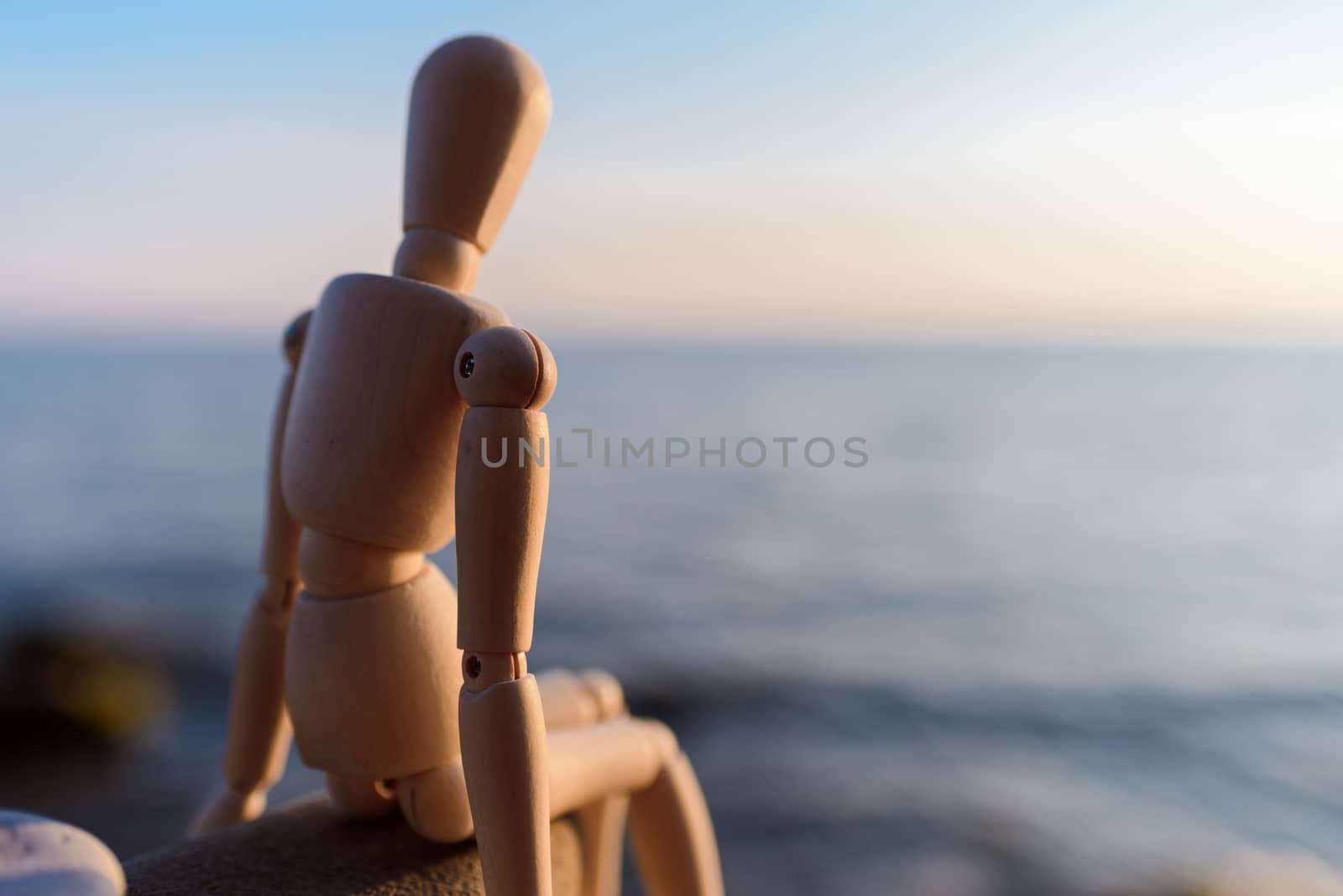 Wooden dummy sitting on the stone at the sea