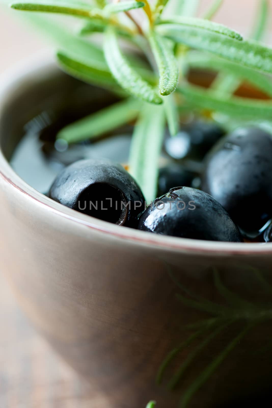 Black olives in clay bowl and rosemary set