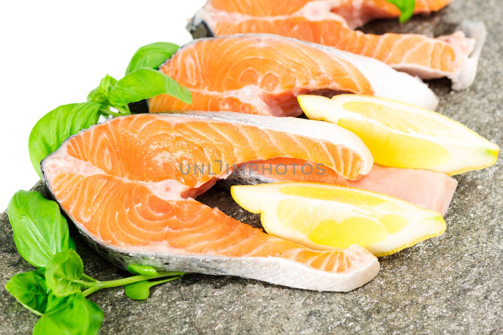 Salmon on stone with basil and lemon isolated on white by Nanisimova