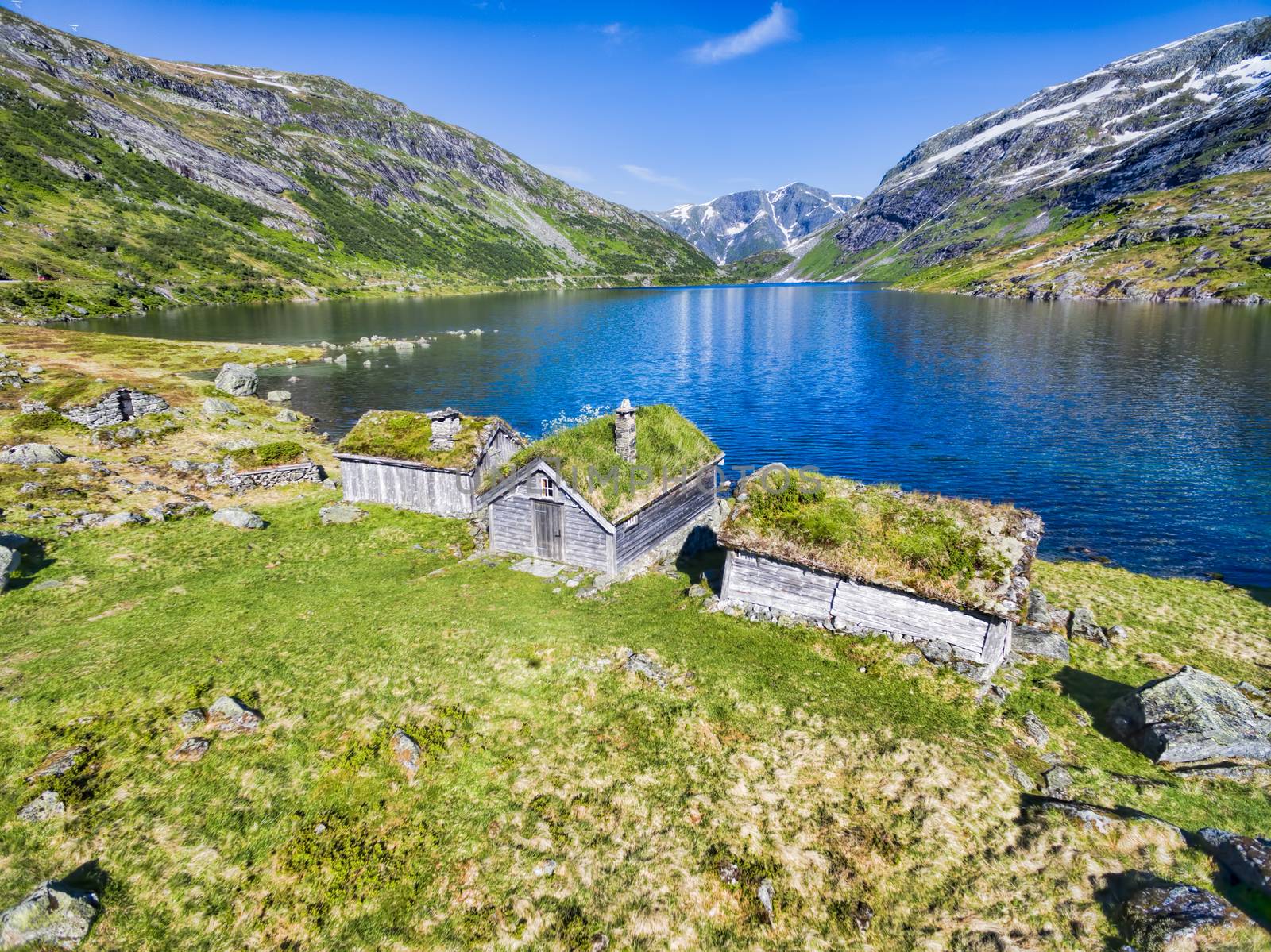 Traditional norwegian huts by picturesque lake surrounded by mountains in Gaularfjellet mountain pass in Norway