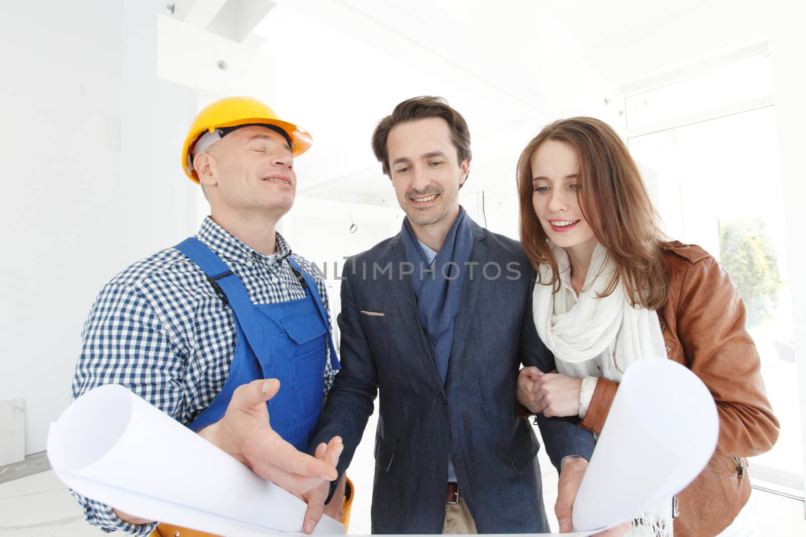 Worker shows construction plan to young couple