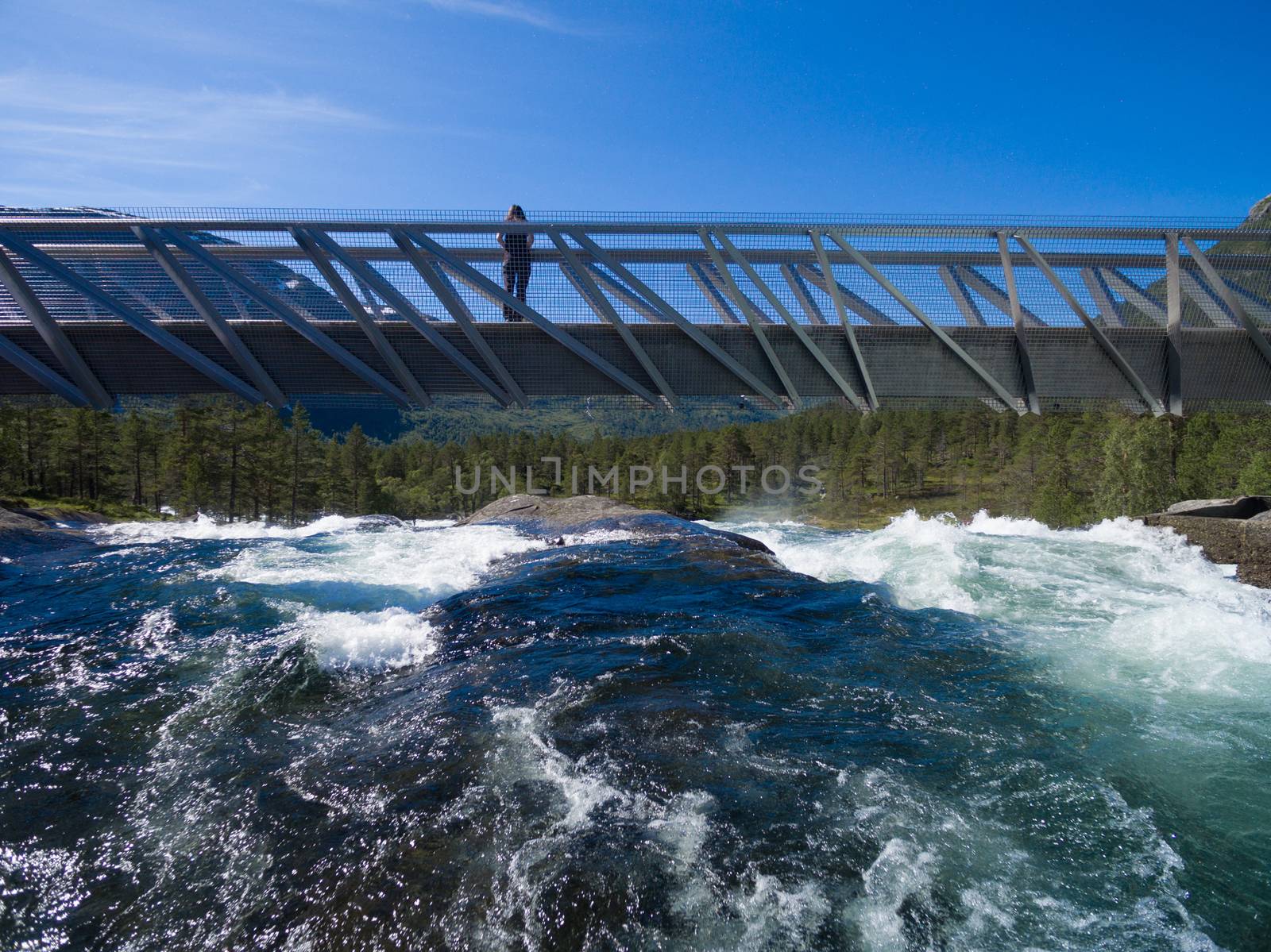 Girl standing on bridge above waterfall Likholefossen on Gaularfjellet tourist national road in Norway